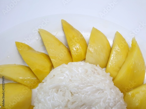 Top view of Thai mango sticky rice topped with coconut cream on white plate isolated on white background, This food is most popular Thai derrest, Kao neaw ma moung is Thai traditional photo