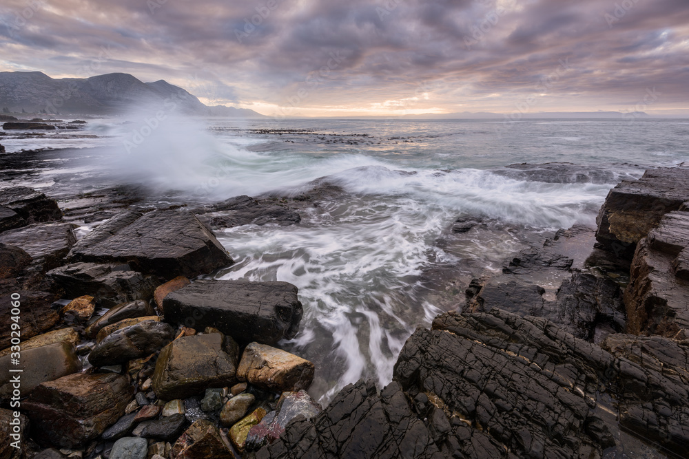 A beautiful early morning seascape photographed on a stormy day at sunrise in Hermanus, South Africa.