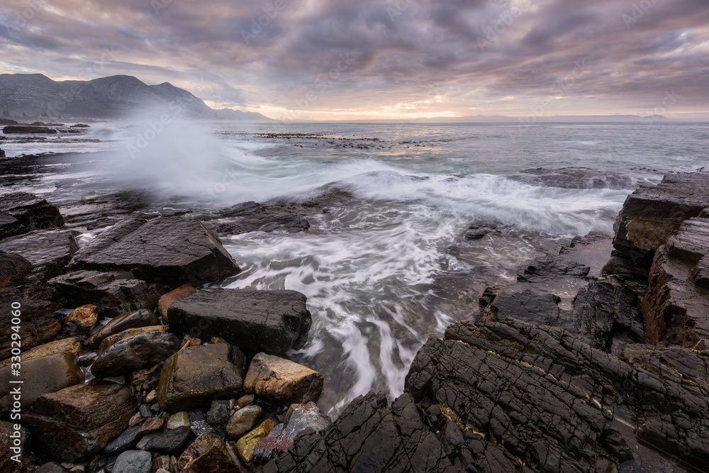 Obraz premium A beautiful early morning seascape photographed on a stormy day at sunrise in Hermanus, South Africa.