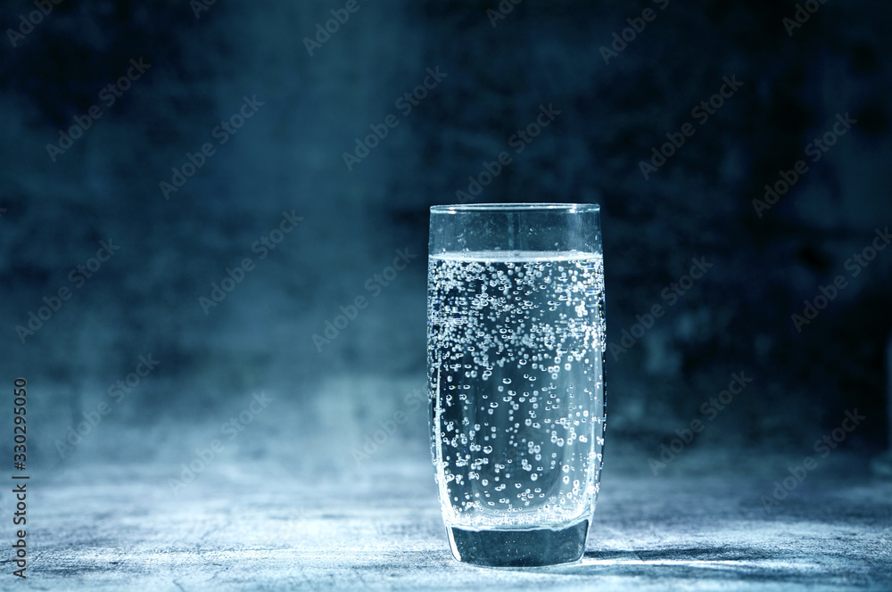 Glass of sparkling water on the grey background Glass of sparkling water on the grey background