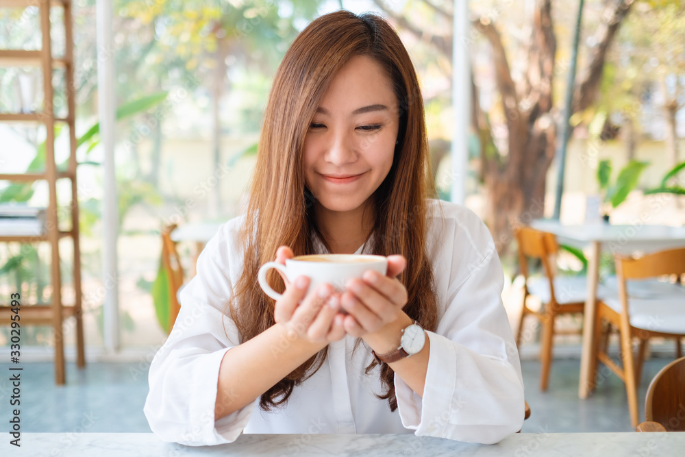 Closeup image of a beautiful asian woman holding a cup of hot coffee Closeup image of a beautiful asian woman holding a cup of hot coffee