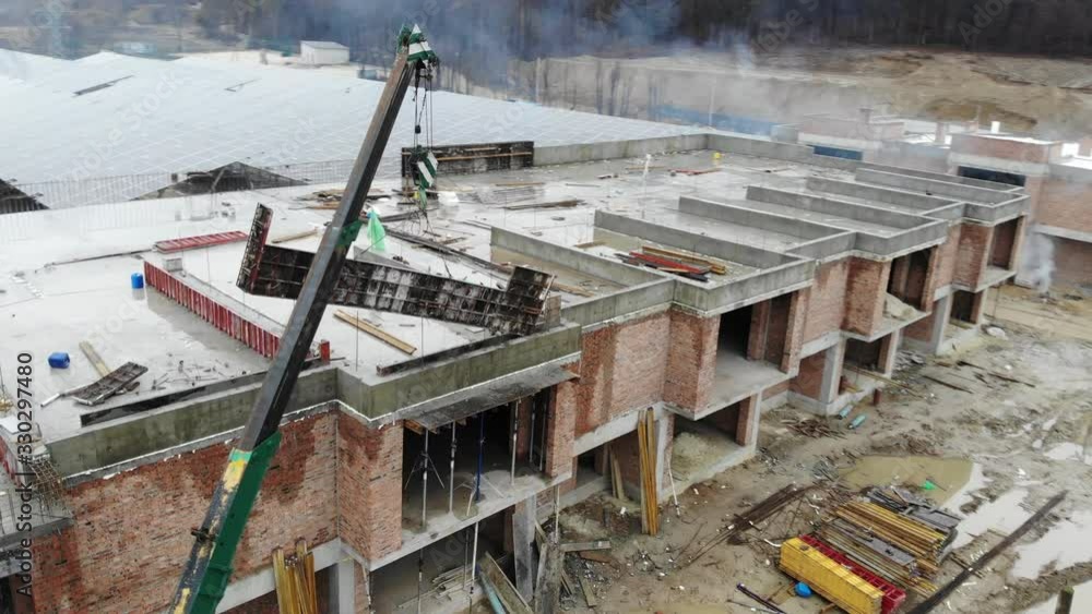 Aerial view of A small construction crane lifts a heavy metal structure. Flying around the construction crane. Aerial view of A small construction crane lifts a heavy metal structure. Flying around the construction crane.