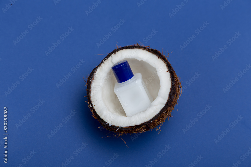 Coconut oil on half coconut on a blue background. The concept of home skin care. Coconut oil on half coconut on a blue background. The concept of home skin care.