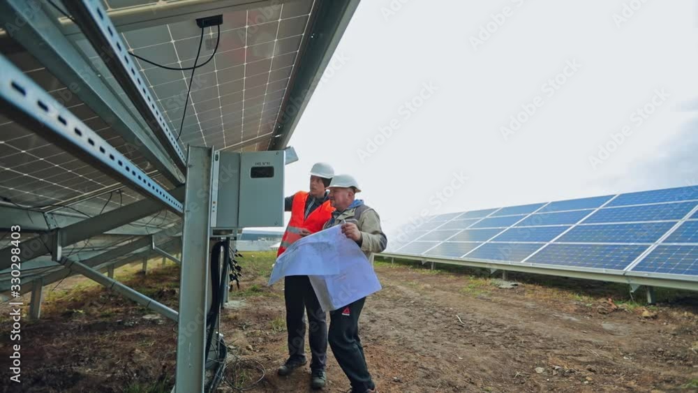 custom made wallpaper toronto digitalTechnicians installing solar panel. Men engineers in helmets connecting photovoltaic panels on the solar farm outdoors.