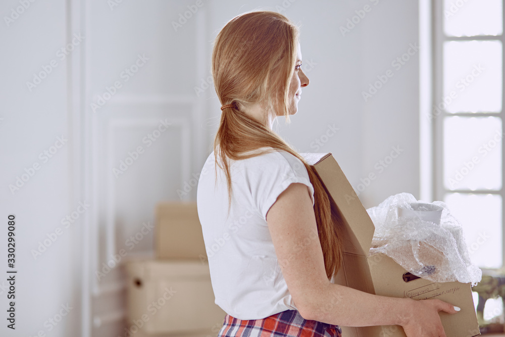 A beautiful single young woman unpacking boxes and moving into a new home A beautiful single young woman unpacking boxes and moving into a new home