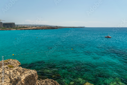 CYPRUS, NISSI BEACH - MAY 12/2018: Tourists swim on catamarans and kayaks in the popular bay of the Mediterranean Sea.