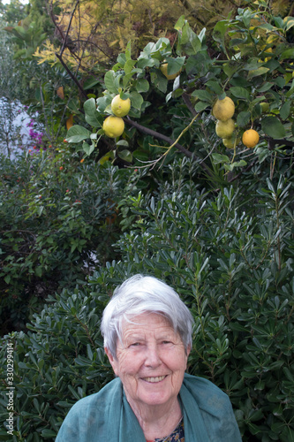 Portrait d'une femme âgée avec des cheveux gris devant des plantes et un citronier photo