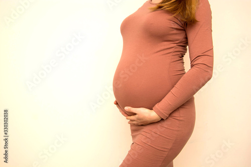 Beautiful pregnant woman with hands around her pregnant belly. Copy space.