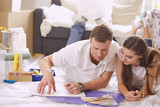 Young Hispanic couple looking at blueprints of new home, high angle view
