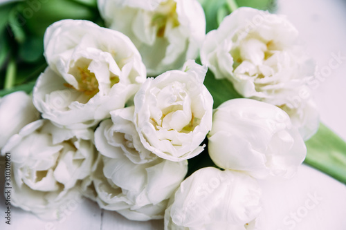 Bouquet of white tulips on a wooden background with space for text.  © elenavah