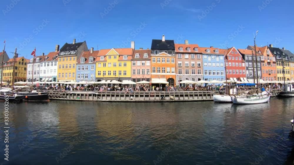Nyhavn Harbor With Tourists Walking Along Street in Copenhagen, Denmark on a Bright Blue Summer Day Nyhavn Harbor With Tourists Walking Along Street in Copenhagen, Denmark on a Bright Blue Summer Day