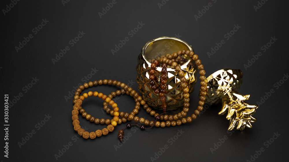 beautiful golden ceramic box in the form of pineapple with wooden necklaces on a black background