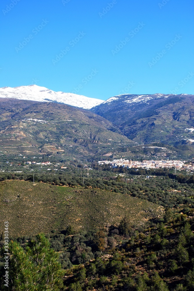 View of the town and countryside in the Vale of Lecrin with views towards the snow capped Sierra Nevada mountains, Orgiva, Spain.