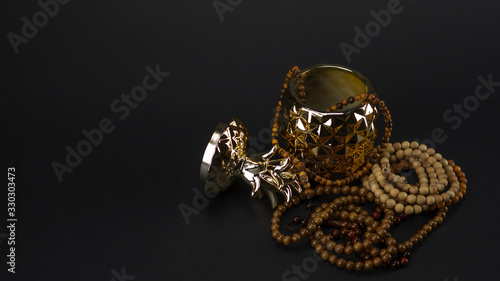 beautiful golden ceramic box in the form of pineapple with wooden necklaces on a black background