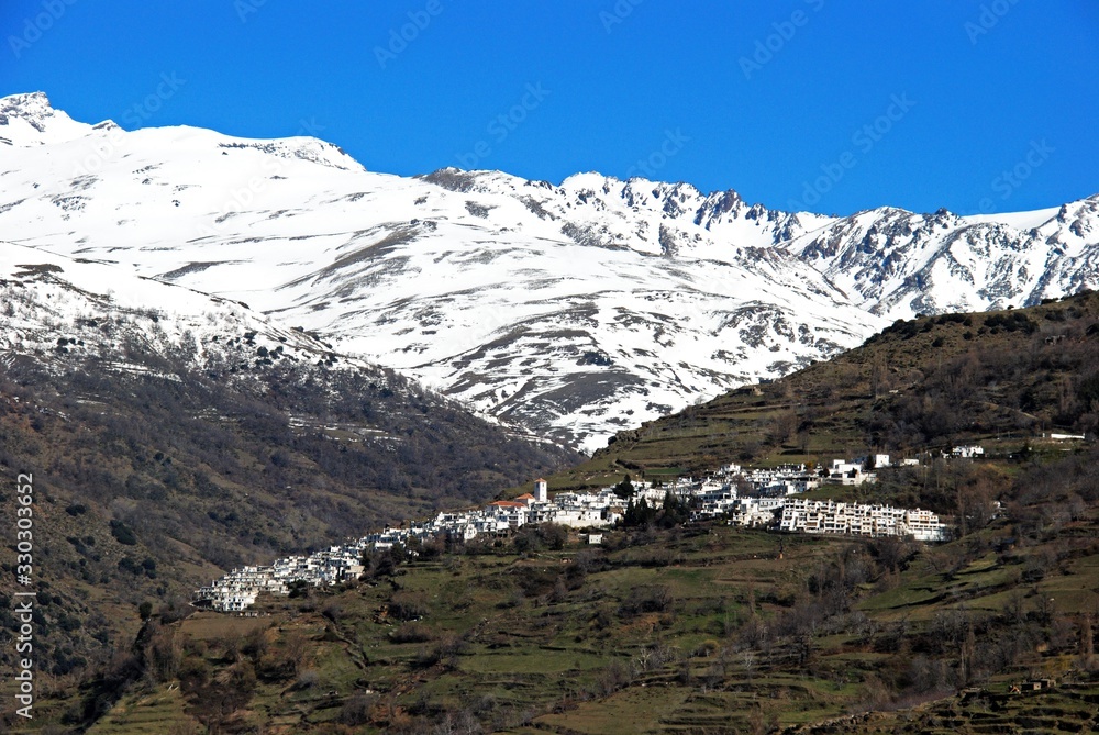 View of the town looking towards the snow capped mountains of the Sierra Nevada, Pampaneira, Spain.