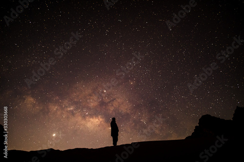 Man standing on desert hill with milkyway and stars