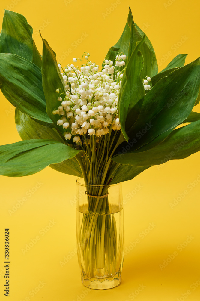 Obraz premium A bouquet of lilies of the valley. A small bouquet of lilies of the valley with white flowers and green leaves