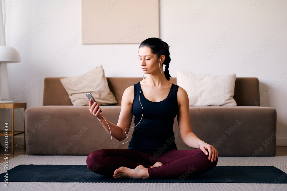 Happy woman doing yoga at home and listening music on the phone