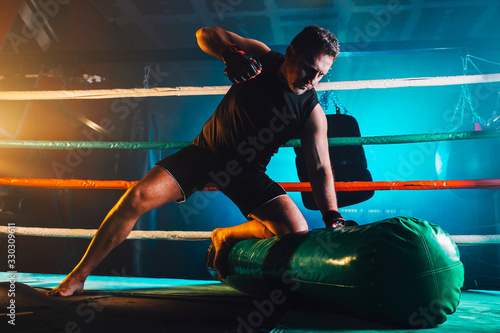 muscular man practicing mma in the boxing ring - ground and pound photo