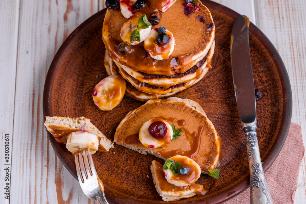 Delicious and lush pancakes with fresh fruits and berries, poured with salted caramel.