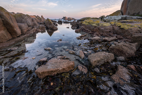 A beautiful early morning seascape, with a golden cloudy sky and rocks and reflections in the foreground, taken at Paternoster, South Africa. photo