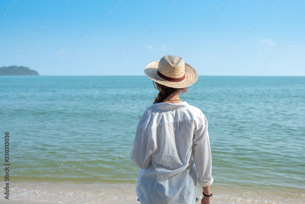 Back view or behind view woman standing on the beach and looking at the sea feel like relax and calm