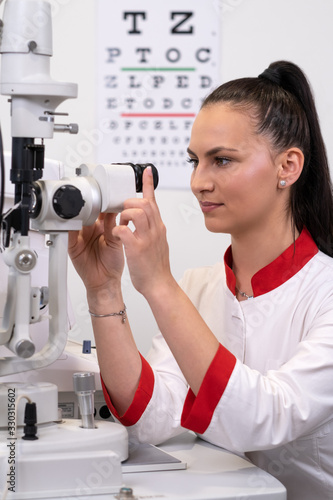 Young female scientist looking through microscope