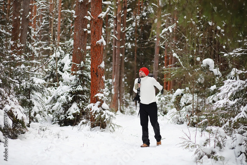 A man travels with a backpack. Winter hike in the forest. Tourist on a walk in the winter in the park. © alexkich