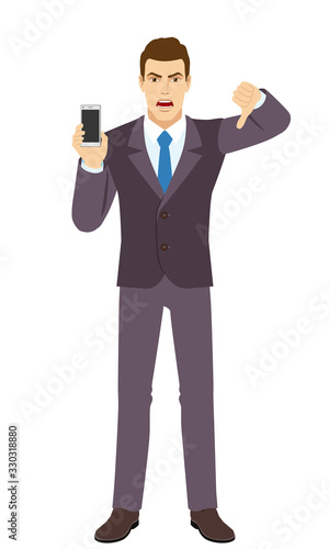 Angry Businessman holding a mobile phone and showing thumb down gesture as rejection symbol. Full length portrait of Businessman in a flat style.