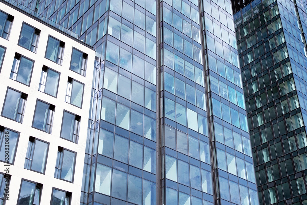 Modern curtain wall made of glass and steel. Blue sky and clouds reflected in windows of modern office building. Modern curtain wall made of glass and steel. Blue sky and clouds reflected in windows of modern office building.