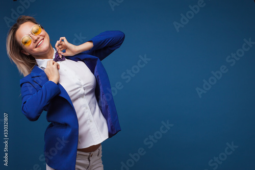 jumping and dancing businesswoman in stylish blue jacket and bow tie. Portrait of a cheerful girl