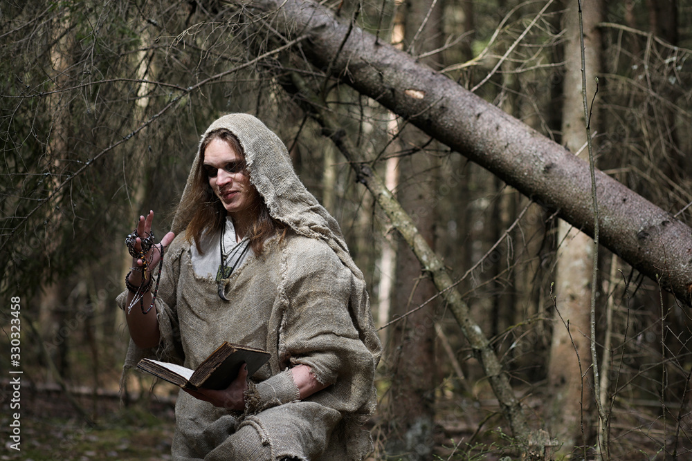 A man in a cassock spends a ritual in a dark forest