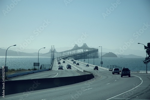 Cars riding through The Richmondâ€“San Rafael Bridge surrounded by the sea in California photo