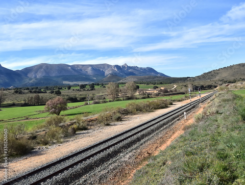 Train track crossing a beautiful landscape with meadows, trees and mountains in Andalusia