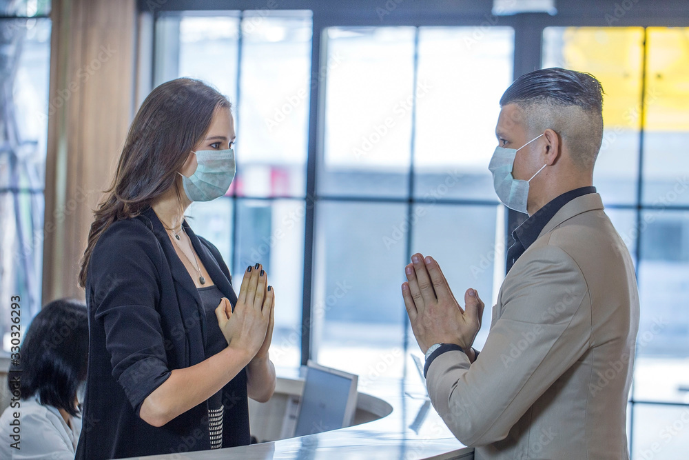 Hotel receptionists raise their hands to pay respect or greet guests to the hotel instead of shaking hands. Covid Disease Prevention Section Hotel receptionists raise their hands to pay respect or greet guests to the hotel instead of shaking hands. Covid Disease Prevention Section