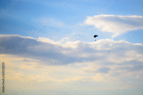 Sunset sky, paratroopers soar among the clouds. Warm summer evening in nature.