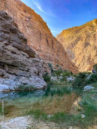 Wadi Shab river canyon, Sultanate of Oman. Natural mountain landscape with green water river and vertical rocky cliffs.
