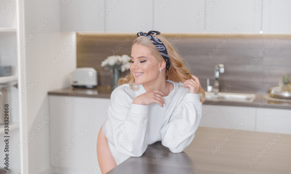 Sexy smiling blonde in headband posing near kitchen table in white sweatshirt and panties Sexy smiling blonde in headband posing near kitchen table in white sweatshirt and panties