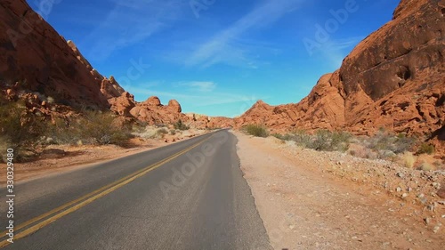 4K. POV view of car driving on road of highway at day in USA. Drive on an empty road in the dark evening. Asphalt with yellow line at new road in Valley of Fire. Nevada state.