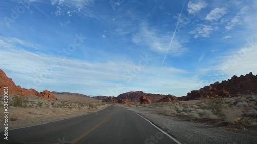 4K. POV view of car driving on road of highway at cloudy day in USA. Drive on an empty road in the dark evening. Asphalt with yellow line at new road in Valley of Fire. Nevada state.