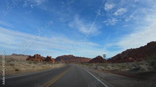 4K. POV view of car driving on road of highway at cloudy day in USA. Drive on an empty road in the dark evening. Asphalt with yellow line at new road in Valley of Fire. Nevada state.