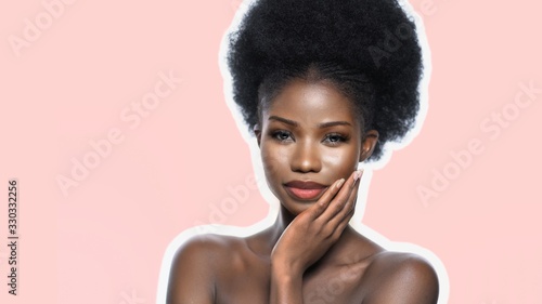 Sexy Afro Woman With Natural Make Up Looking Confidently, Front View Of Pretty Model With Naked Shoulders, She Touches Her Face With Hand, Isolated On Pink Back