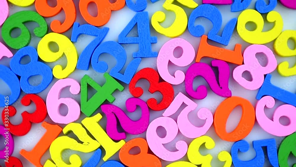 Colorful numbers are scattered and slowly rotate on a white background. The numbers are wooden, bright, and of various colors. Colorful numbers are scattered and slowly rotate on a white background. The numbers are wooden, bright, and of various colors.