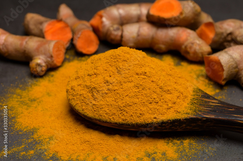 Turmeric powder and fresh turmeric (curcumin) on black background. 