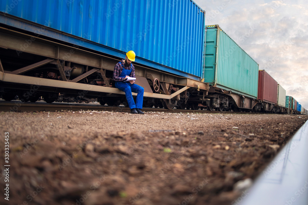 Fotka „Railway worker keeping track of arrived shipping cargo ...