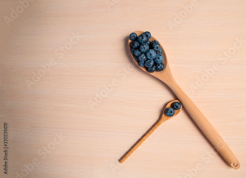 Fresh blueberries lie in a wooden spoon on a natural wooden background. Eco products for human health. Healthy eating concept flat lay. Copy spase