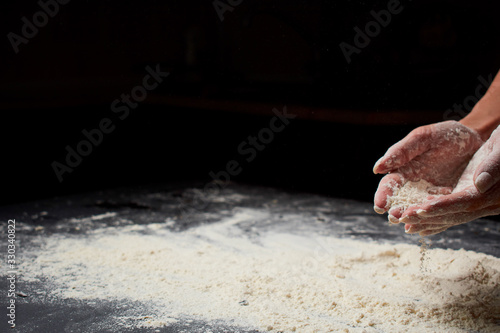 Professional Female cook sprinkles dough with flour, prepared for baked bread