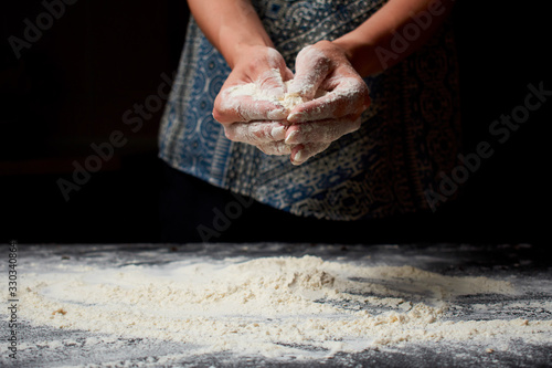 Professional Female cook sprinkles dough with flour, prepared for baked bread