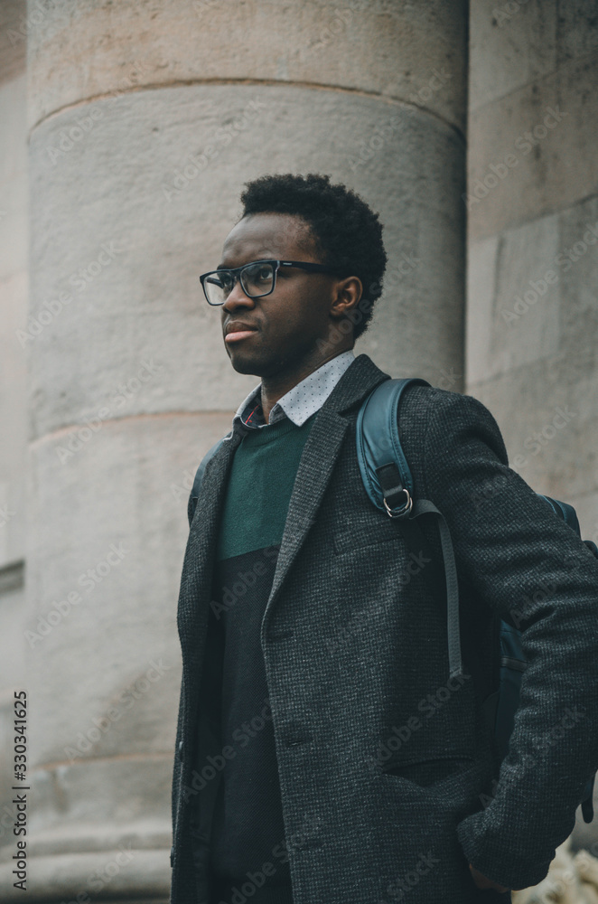 Black student with glasses and a bag in his shoulder