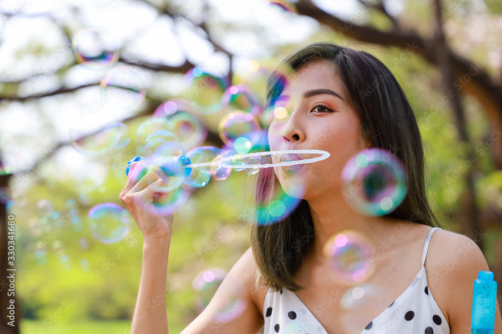 Outdoor autumn summer portrait of asian young beautiful happy woman making soap bubbles in park. Her Joyous happy in white dress. Holiday relaxation ideas Outdoor autumn summer portrait of asian young beautiful happy woman making soap bubbles in park. Her Joyous happy in white dress. Holiday relaxation ideas
